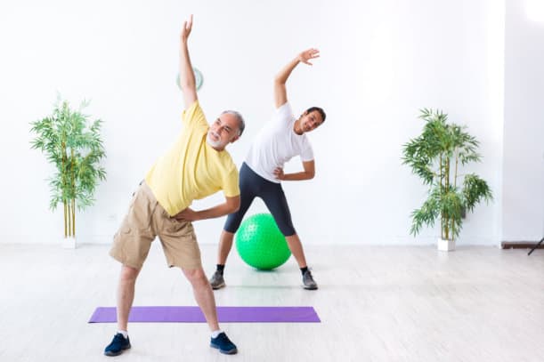 A senior citizen and a young man exercising together