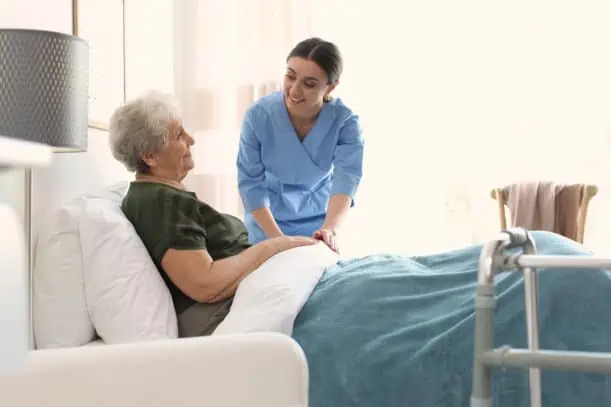 A senior citizen in bed while talking to a caregiver