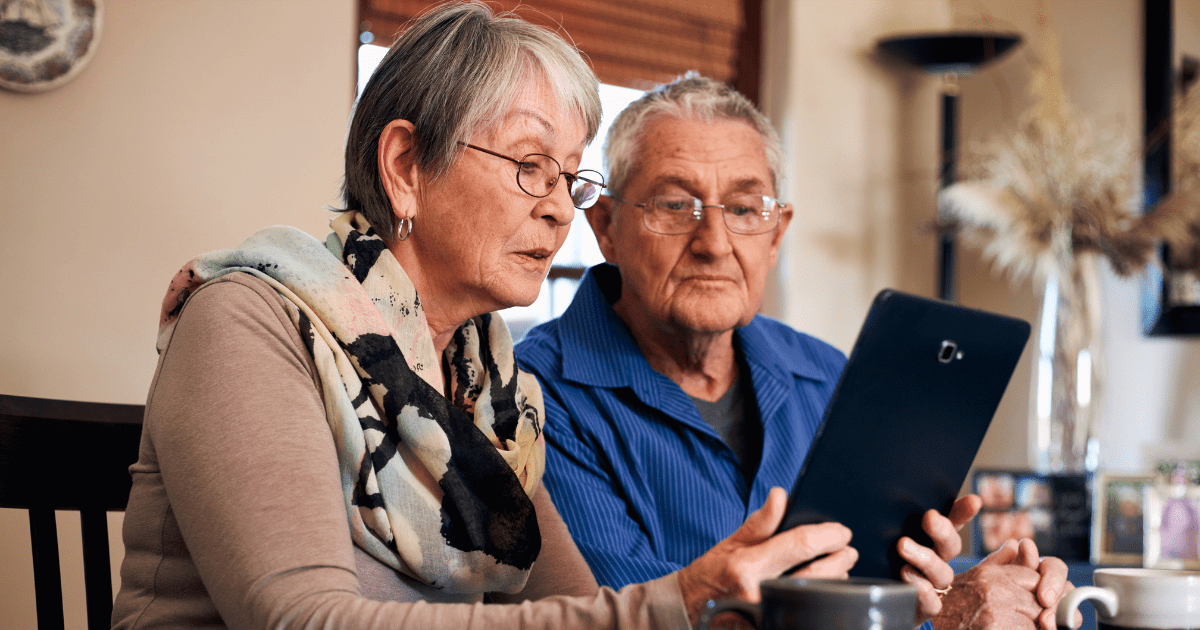 Two senior citizens looking at a tablet